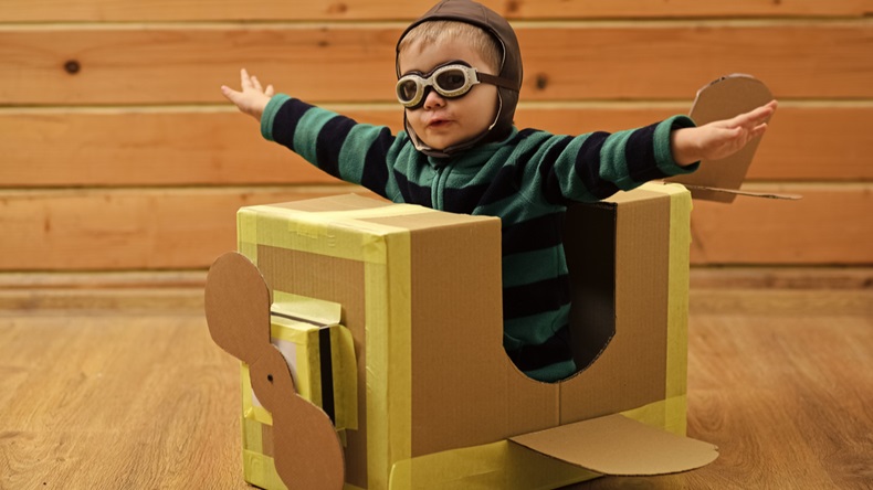 child piloting carboard plane