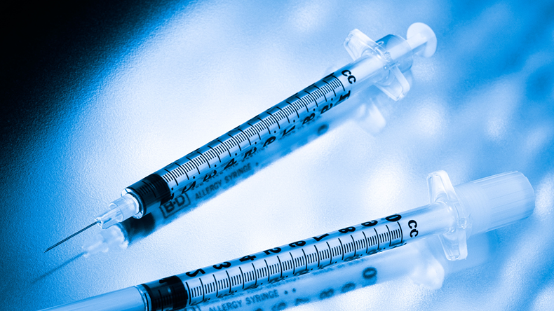 Two medical syringes beautifully displayed on a dabbled background with a blue monochromatic look