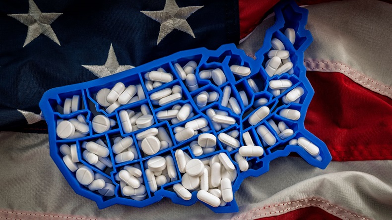 Healthcare, opioid epidemic and drug abuse concept with the map of USA filled with oxycodone and hydrocodone pharmaceutical pills on the American flag 