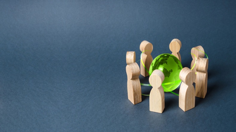 Wooden figures of people gathered around green globe