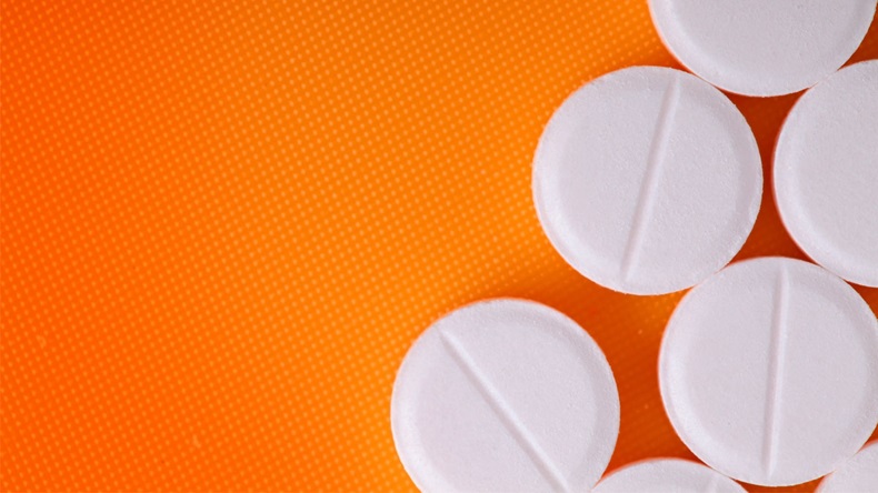 White pills on an orange background. - Image 