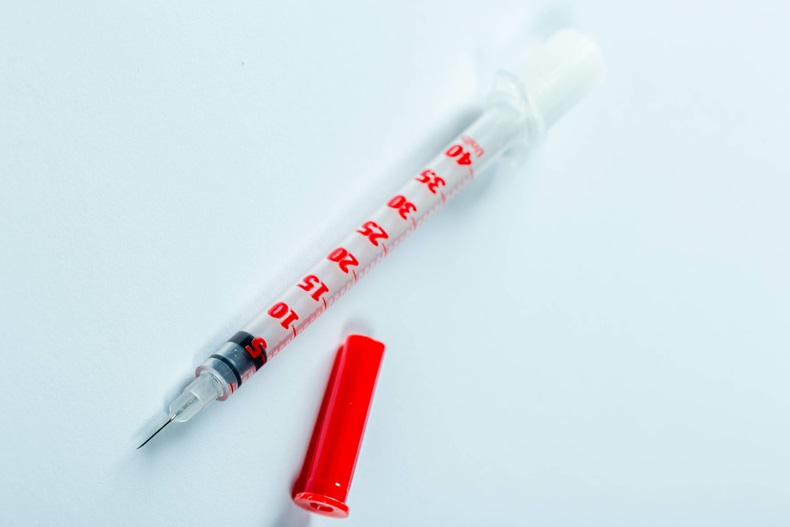 Insulin syringe on light blue background