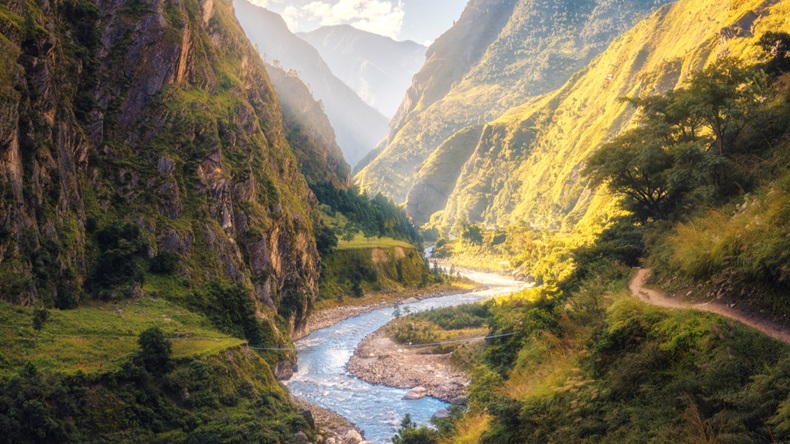 Colorful landscape with high Himalayan mountains, beautiful curving river, green forest, blue sky with clouds and yellow sunlight at sunset in summer in Nepal. Mountain valley. Travel in Himalayas - Image 