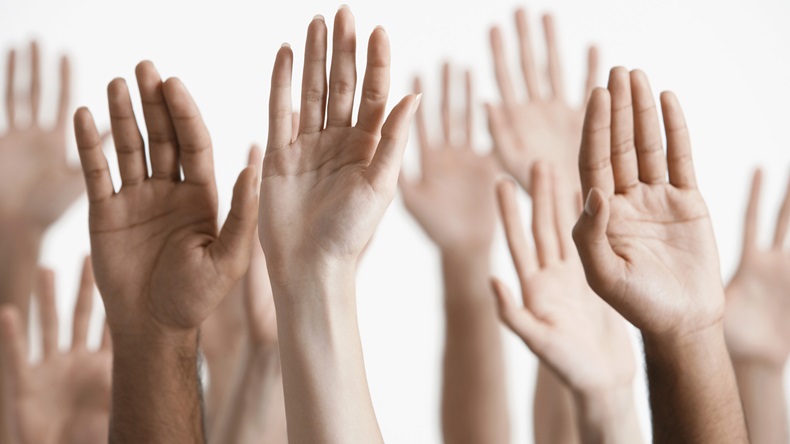 Closeup of multiethnic men and women raising hands against white background