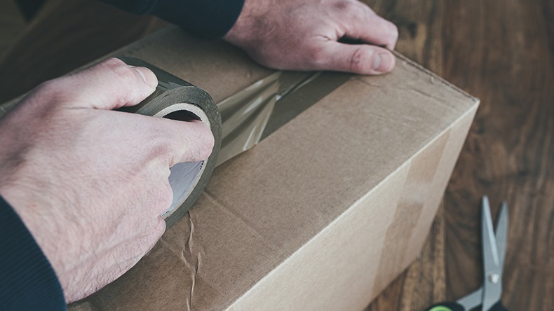 Close-up of person sealing up shipping box with parcel tape