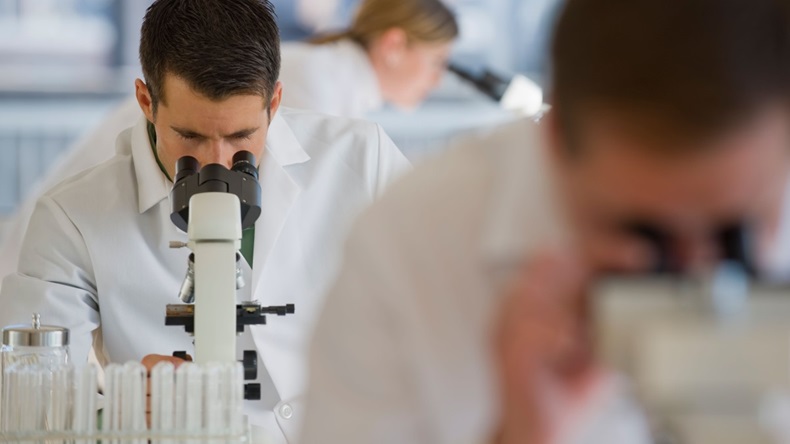 Scientists using microscopes pharmaceutical laboratory