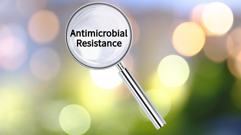 Magnifying lens over background with text Antimicrobial resistance, with the blurred lights visible in the background.