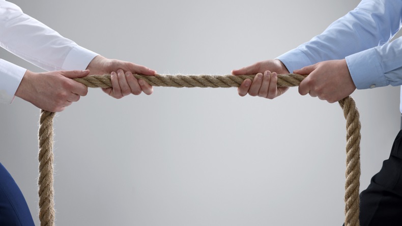 two people in business clothes engaging in a tug of war