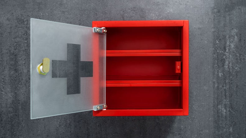 Open red metal empty medicine cabinet hanging on a dark gray marble wall background