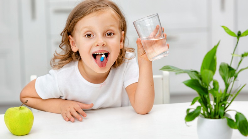 child with a pill dragee on her tongue. Taking medicine, vitamin supplements, health care, treatment concept.