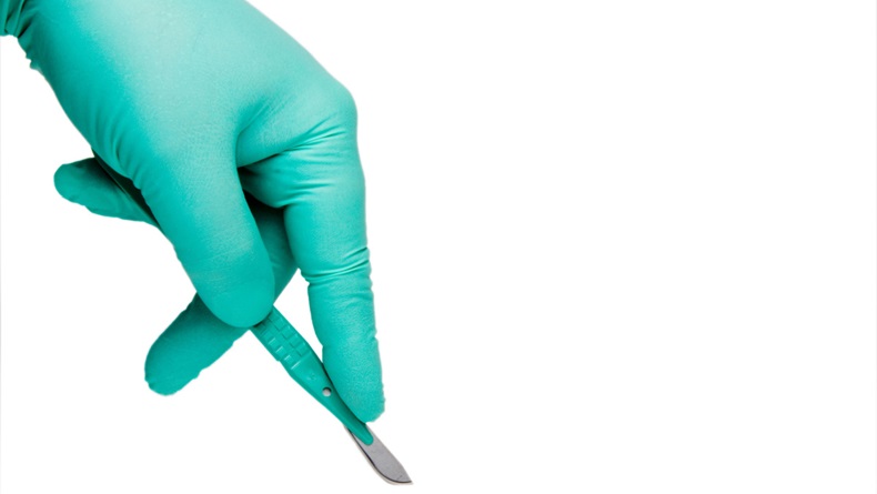 close up of gloved hand holding a scalpel 
