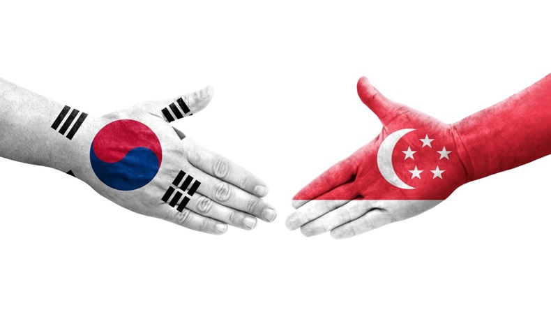 Handshake between South Korea and Singapore flags painted on hands, isolated transparent image.