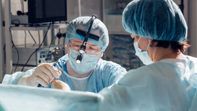 two people in operating room performing surgery 