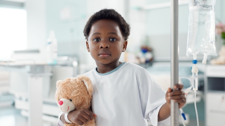 young boy in hospital holding teddy bear and IV pole