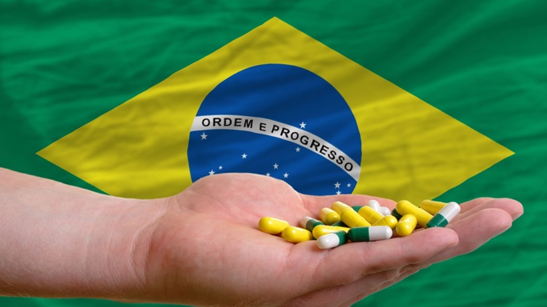 man holding capsules in front of complete wavy national flag of brazil