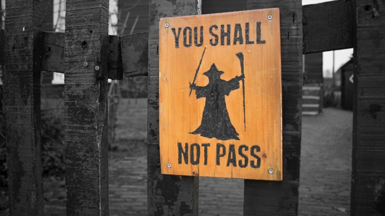 Dark fence with sign with a wizard that says "you shall not pass"