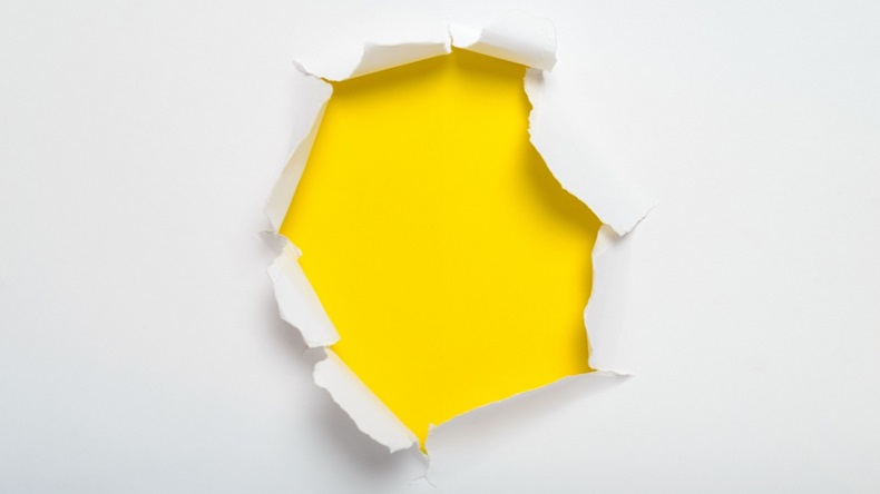 white piece of paper with hole ripped in center revealing yellow background.