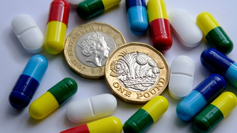 Pile of different colouful pills placed around two british pound coins