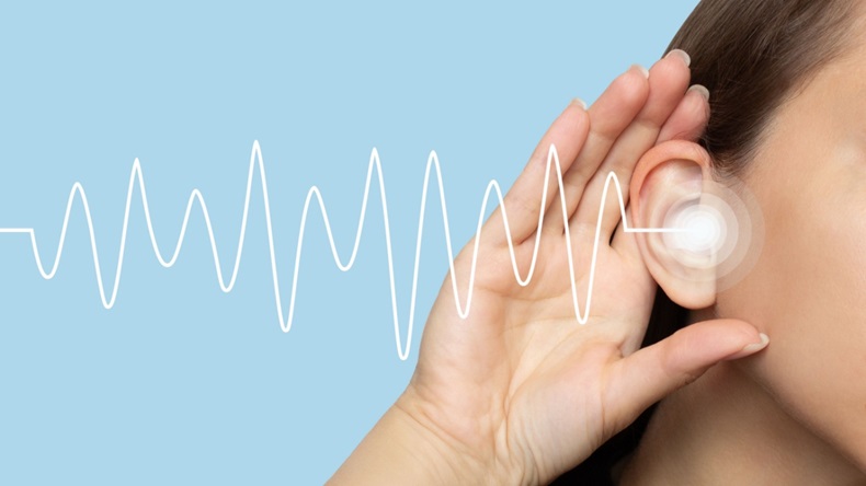 A woman puts her hand to her ear and listens, isolated on a blue background with sound waves. Hearing problems, ear diseases, noise.