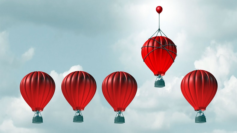 Competitive edge and business advantage concept as a group of hot air balloons racing to the top but an individualleader with a small balloon attached giving the winning competitor an extra boost.