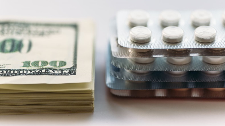 Bundle of money and pack of medication tablets or drug pills, close-up. Expensive health care concept, selective focus